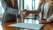 © Adobe Contributor - Business handshake. Businessman and businesswoman shaking hands over a signed contract.