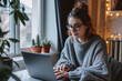 © Dennis - A young woman working from home on her laptop, working remotely, home office