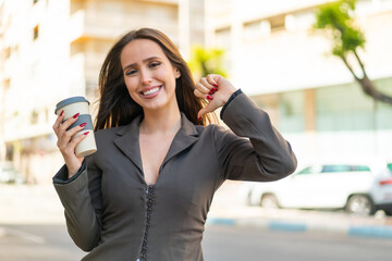 Poster - Young woman holding a take away coffee at outdoors proud and self-satisfied