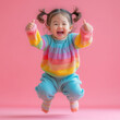 Fisheye view of a japanese kid girl jumping and thumbs pink background.