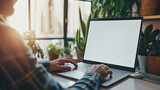 Fototapeta  - Over shoulder shot of a young man using computer laptop in front of an blank white computer screen in home