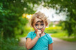 © yanadjan - A child looks through a magnifying glass in nature. Selective focus.
