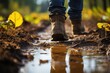 A rugged individual braves the elements, their jeans caked in mud as they stand amidst a sea of yellow flowers, showcasing their sturdy outdoor footwear while walking through a puddle on a nature pat