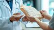 Person in a lab coat receiving a package from another person, representing a delivery or transfer of goods, possibly medical supplies or documents, in a healthcare setting.