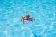 © Alex - Smiling baby girl swims with an inflatable ring in a summer pool