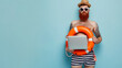 bearded man with a man bun wearing sunglasses, stripped swim shorts, and an orange life preserver, holding a laptop in front of his bare chest against a light blue background