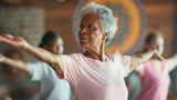 Fototapeta  - elderly woman with grey hair is practicing yoga with her eyes closed and arms extended, surrounded by others in a class setting