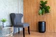 Contemporary home decor featuring a comfortable grey armchair, a stylish fiddle leaf fig in a sleek black pot, and natural bamboo wall paneling..