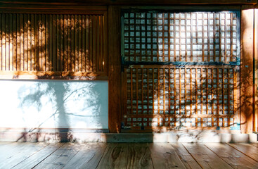 Wall Mural - Scenic view of tree shadows cast on the wall of a traditional Japanese house with a grid door, a wooden window and a floor of old natural wood panels, in Shoren-In Buddhist temple in Kyoto, Japan