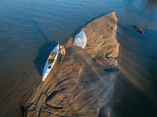 Wall Mural - male paddler with a decked expedition canoe on a sandbar with ice floe - South Platte River in eastern Colorado