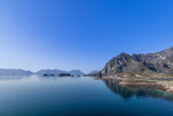 Fototapeta Natura - Tranquil waters mirror the rugged mountains of Lofoten, with traditional fish racks in Norway's serene landscape