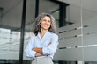 © insta_photos - Happy mature business woman leader standing in office looking away. Smiling confident older middle aged professional lady corporate leader, senior female executive or entrepreneur portrait.