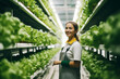 Cheerful female farmer caring for lettuce in a hydroponic indoor farm