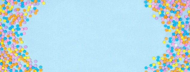 Aufkleber - Colorful candy sprinkles double border. Overhead view on a blue banner background. Pastel Easter color theme. Copy space.