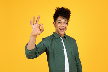 Wall Mural - Positive black guy showing okay gesture, yellow background