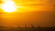 Panoramic view of orange sunset sunrise sky and silhouettes of port cranes in the Mediterranean port of Alicante, Spain.