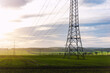 © Kirill Gorlov - Scenic view of electricity pylons stretching across green fields warm sunset sky background. Electric power supply high voltage metal tower in Europe