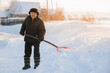 © Parilov - Elderly man cleaning snow with shovel after snowstorm. Worker old pensioner works as janitor, sunlight.