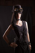 Plastic woman mannequin wearing steampunk clothes and accessories posing on a black background with a split lighting effect