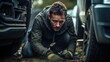 © Fotograf - A man is fixing a car tire on the ground. This image can be used to depict car maintenance or roadside assistance