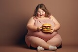 Fototapeta Sport - Fat girl with hamburger on a brown background. The concept of fast food. Child with obesity. Overweight and obesity concept. Obesity Concept with Copy Space.