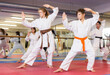 © JackF - Kids in karate uniform exercising kata during group training with trainer.