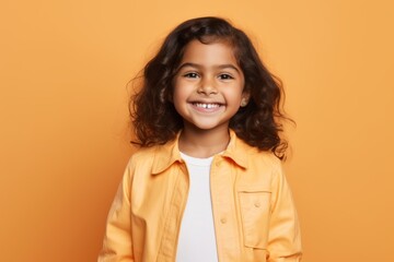 smiling little african american girl in yellow jacket on orange background