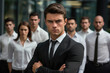 © vefimov - Professional man dressed in suit stands confidently in front of group of people. This image can be used to depict leadership, teamwork, or business presentations