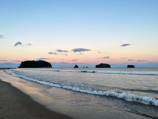 Wall Mural - Whangamata Beach, where the sun gracefully sets, casting warm hues across the sky, and a full moon rises