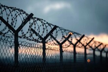 As The Fiery Sunrise Painted The Sky With Hues Of Orange And Pink, The Barbed Wire Fence Stood Tall, A Symbol Of Both Protection And Imprisonment, Against The Backdrop Of A Darkening Cloud-filled Sky
