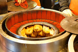 Fototapeta Uliczki - A stall vendor baking in a clay oven the Hujiao Bing (a crispy roasted bun stuffed with pork, scallion, black pepper; one of local people's favorite street-foods) in Raohe Night Market, Taipei Taiwan