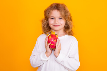 Wall Mural - Kid hold dragon fruit in studio. Studio portrait of cute child with dragon fruit isolated on yellow background, copy space.