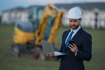 Wall Mural - Civil engineer worker at a construction site. Engineer man in front of house background. Confident engineer worker at modern home building construction. Hispanic civil engineer in helmet.