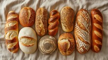  A Bunch Of Different Types Of Breads Lined Up In A Row On Top Of A Sheet Of Wax Paper.