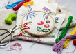 The process of hand embroidering a napkin with colored threads on white fabric.