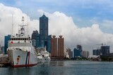 Fototapeta Uliczki - Patrol ships of Coast Guard Administration anchored in Kaohsiung Harbor and the famous landmark 85 Sky Tower standing among skyscrapers in background on a sunny cloudy summer day, in Taiwan, Asia