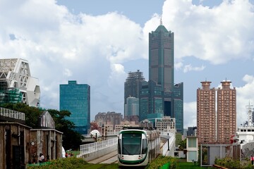 Wall Mural - Cityscape of Kaohsiung, a vibrant metropolis in Southern Taiwan, with 85 Sky Tower standing among skyscrapers in background & a metro train traveling on a light rail overpass by the Pier-2 Art Center