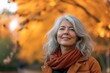 Cute mature woman with gray hair, enjoying autumn outdoors