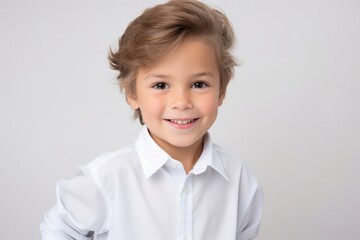 Portrait of a cute little boy in a white shirt on a gray background