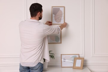 Poster - Man hanging picture frame on white wall at home