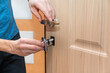 Installation and replacement of door locks. Door repair. A locksmith installs door hardware.