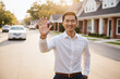 © EliteLensCraftImages - Smiling Asian Businessman Waving His Hand in Modern American Suburb on His Way to Work, Casual.
