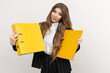 © makedonski2015 - A businesswoman poses with yellow folders in her hand, signalling her attention to detail and organisation skills