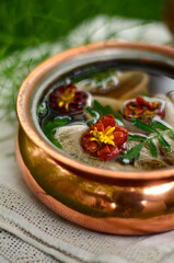 Wall Mural - Marigold flowers in water in a copper saucepan, herbal tea, decoction of medicinal plants, close-up