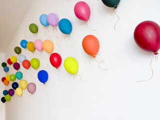 Colorful balloons flying on a white wall