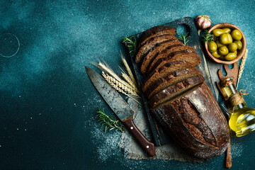 Wall Mural - Rye sourdough bread with flax cut on a board. Fresh bread on a black background. Top view.