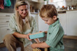 © Halfpoint - Mom packing snack for her son for school. Putting lunch box with healthy snack into his school bag for lunch.