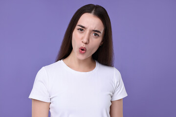 Wall Mural - Portrait of surprised woman on violet background