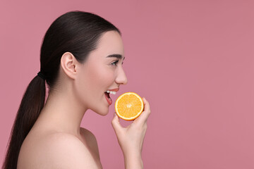 Canvas Print - Beautiful young woman with piece of orange on pink background. Space for text