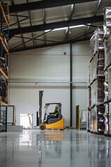 Wall Mural - Side view of forklift in warehouse with male driver. Warehouse worker preparing products for shipmennt, delivery, checking stock in warehouse.